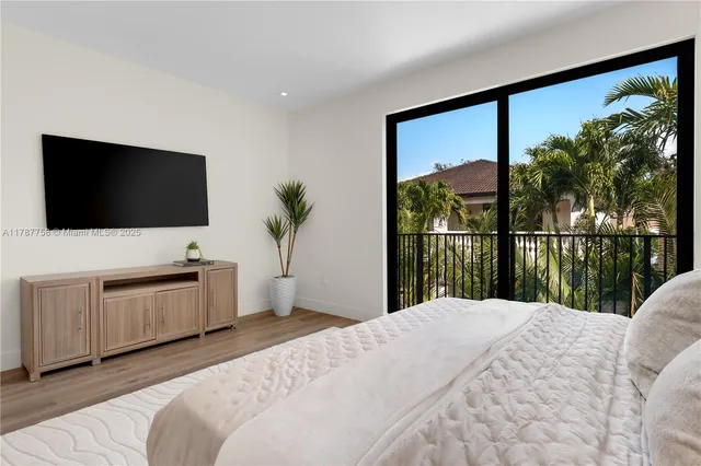 a bedroom with a large bed and a flat tv screen on dresser