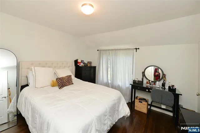 a bedroom with a bed and a dresser with mirror