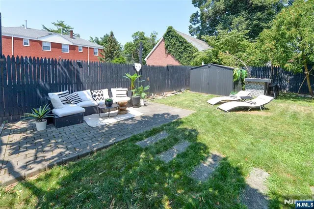 a view of a backyard with couches plants and large tree