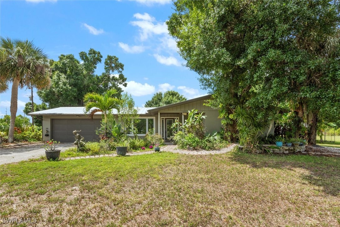 13951 Rod And Gun Club Road Fort Myers, FL 33913 - Photo 5 of 49 a front view of a house with garden and trees