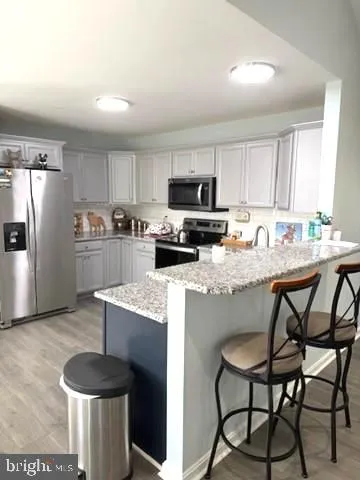 a kitchen with stainless steel appliances granite countertop a dining table chairs refrigerator and sink