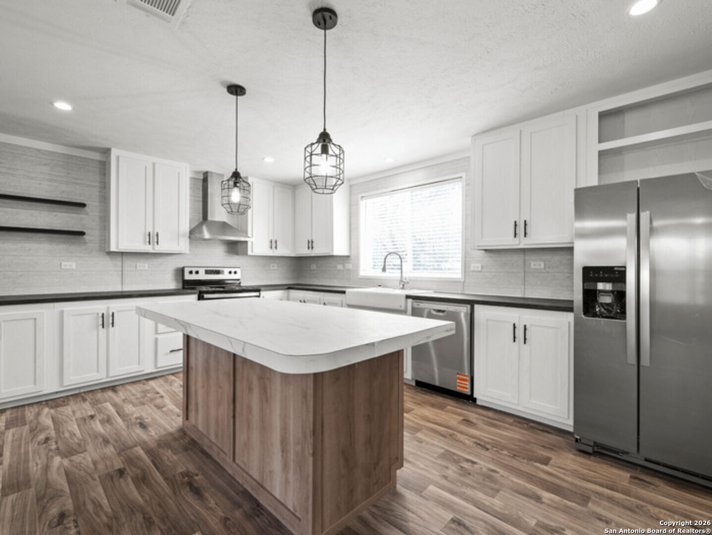 1144 Turkey Canyon Drive Spring Branch, TX 78070 - Photo 8 of 23 a kitchen with stainless steel appliances granite countertop a sink a stove a refrigerator and white cabinets with wooden floor