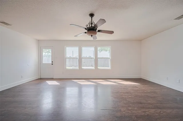 a view of an empty room with window and wooden floor