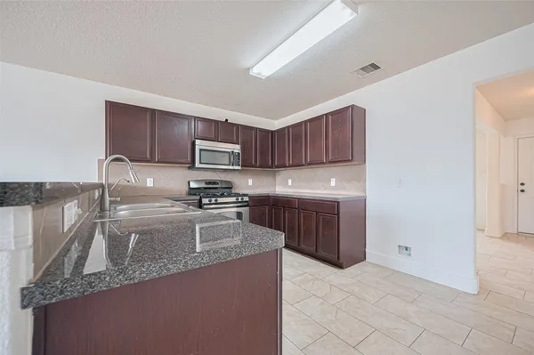 a kitchen with a sink a stove top oven and wooden cabinets
