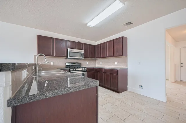 a kitchen with a sink a stove top oven and wooden cabinets