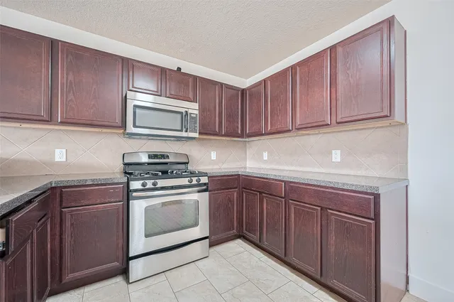 a kitchen with granite countertop wooden cabinets and stainless steel appliances