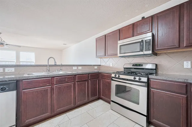a kitchen with stainless steel appliances granite countertop a stove microwave and sink