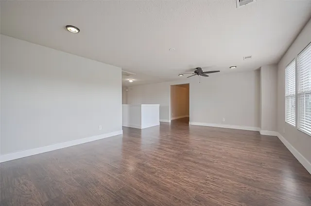 a view of an empty room with a window and wooden floor