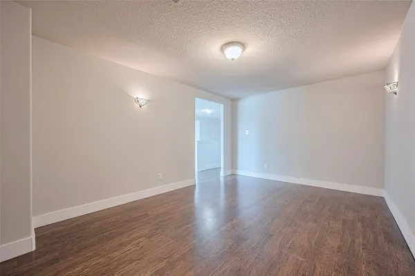 a view of an empty room with wooden floor and closet
