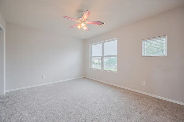 an empty room with windows and fan