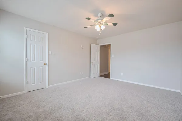 a view of an empty room with a chandelier fan