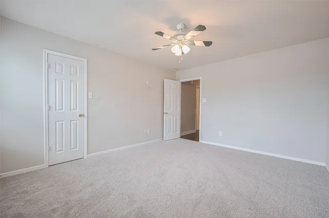 a view of an empty room with a chandelier fan