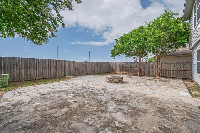 a view of a backyard with wooden fence and a large tree