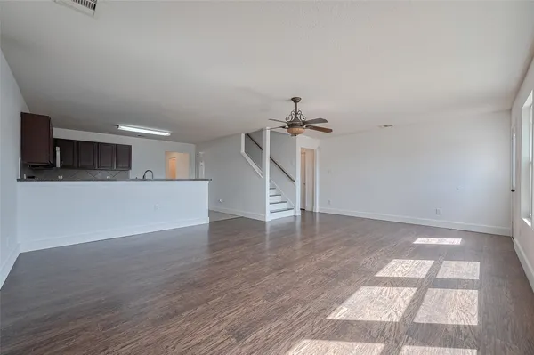 a view of a livingroom with wooden floor and a kitchen space