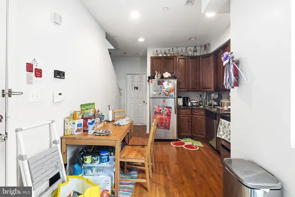 a kitchen with stainless steel appliances a refrigerator and a wooden floor