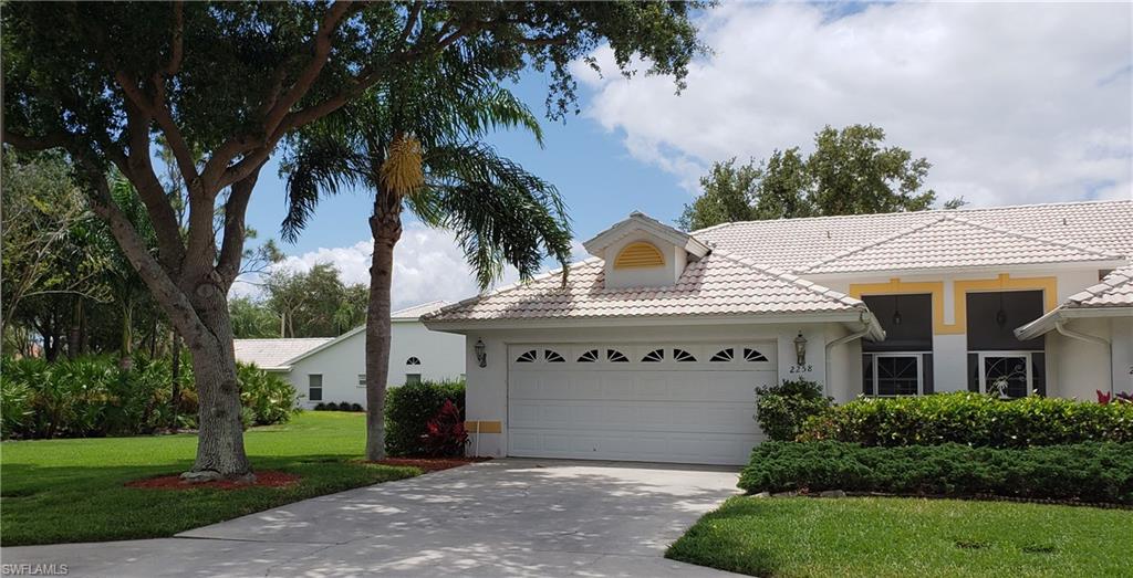 2258 Stacil Circle, Unit 1 Naples, FL 34109 - Photo 2 of 28 a view of a white house with a small yard and a large tree