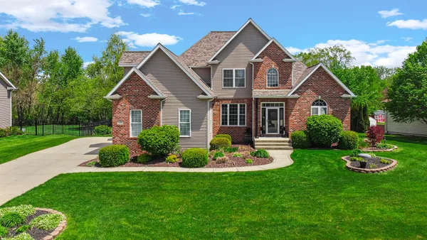 a front view of a house with a yard and green space