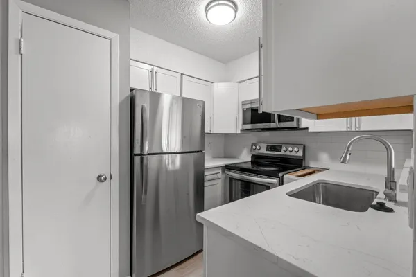 a kitchen with stainless steel appliances sink a refrigerator and a stove