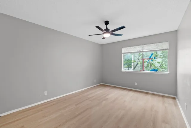an empty room with a window and a fan