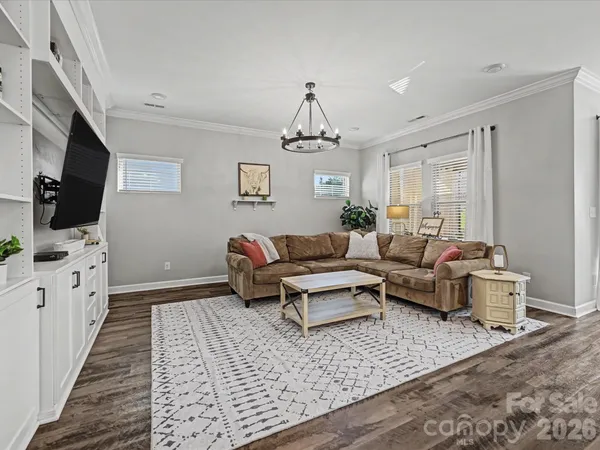 a living room with furniture a flat screen tv and a chandelier