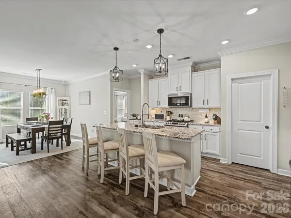 a kitchen with stainless steel appliances a dining table chairs stove and cabinets