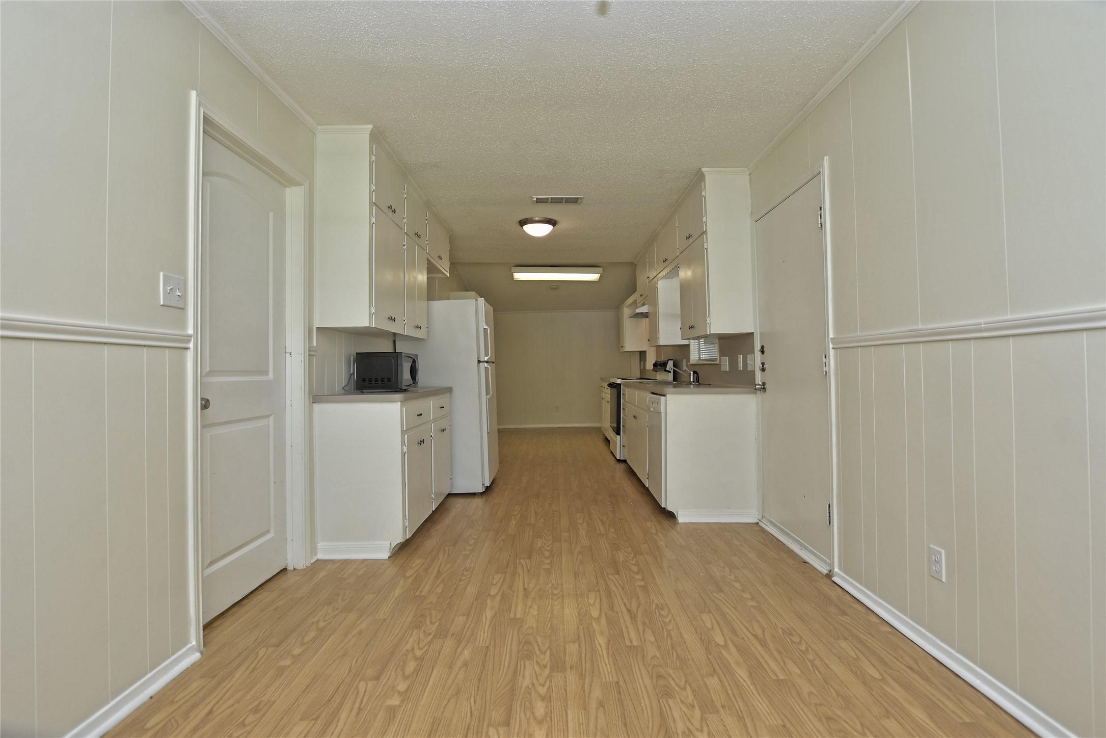 16013 Edwards Drive Austin, TX 78734 - Photo 11 of 30 Kitchen featuring white cabinetry, light countertops, a textured ceiling, light wood-type flooring, and white appliances
