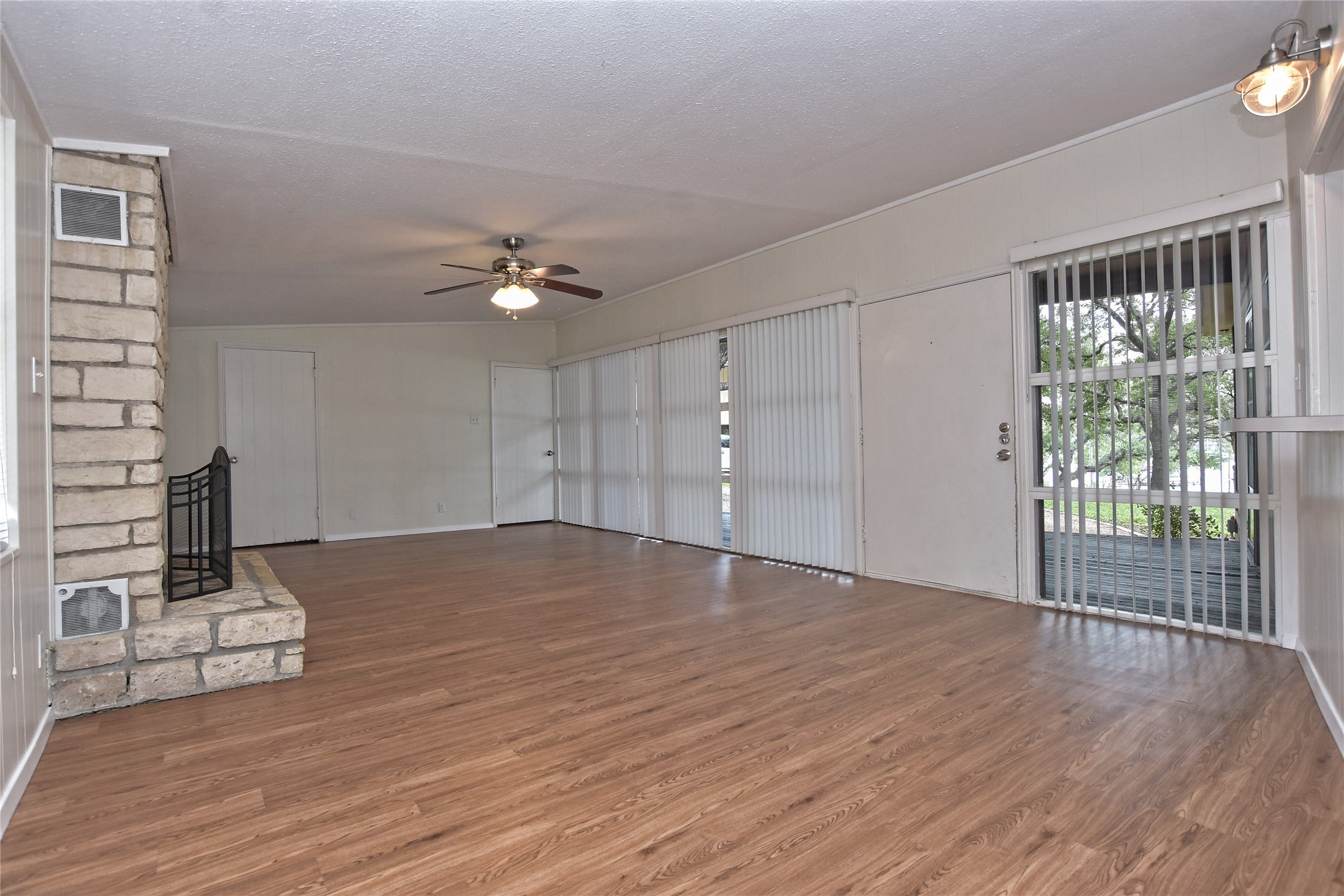 16013 Edwards Drive Austin, TX 78734 - Photo 5 of 30 Unfurnished living room with ceiling fan, wood finished floors, a textured ceiling, and a brick fireplace