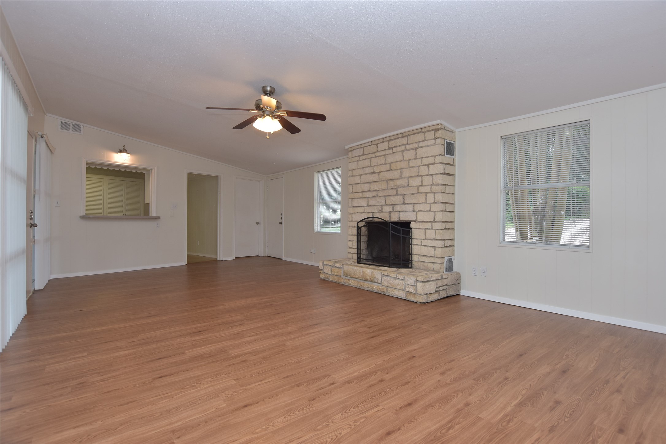 16013 Edwards Drive Austin, TX 78734 - Photo 7 of 30 Unfurnished living room featuring ornamental molding, a large fireplace, wood finished floors, a ceiling fan, and vaulted ceiling