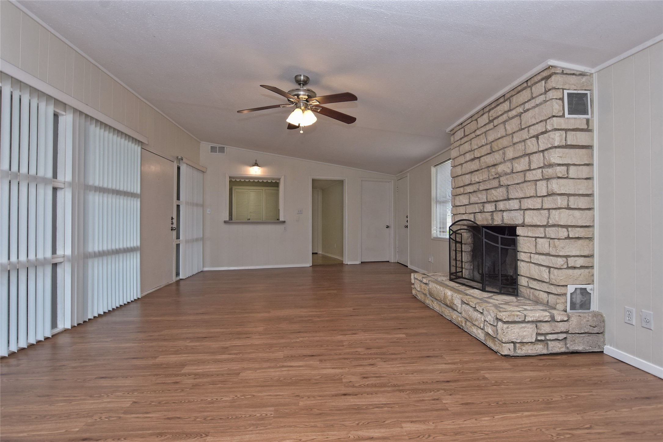 16013 Edwards Drive Austin, TX 78734 - Photo 8 of 30 Unfurnished living room featuring a ceiling fan, a fireplace, wood finished floors, crown molding, and vaulted ceiling