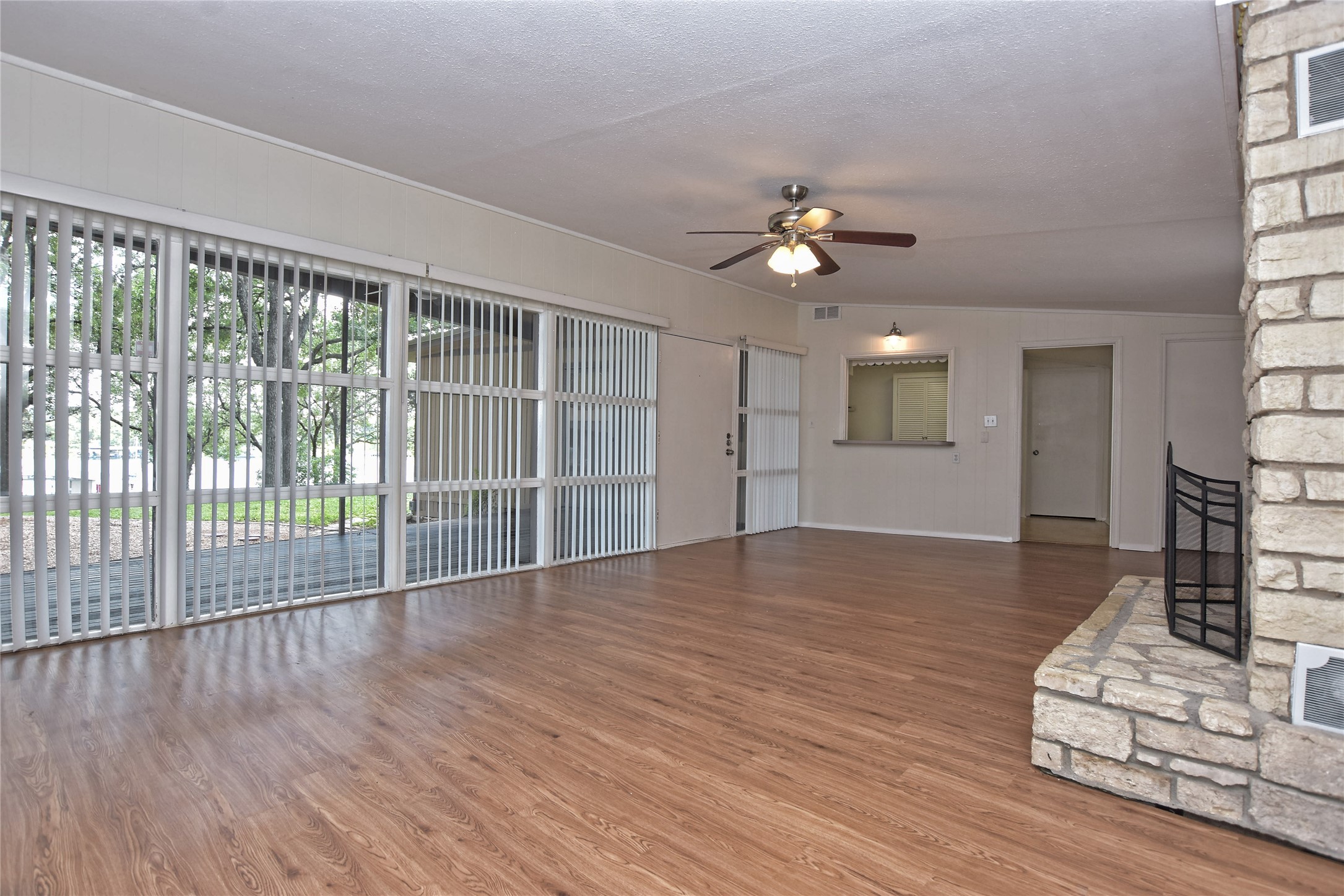 16013 Edwards Drive Austin, TX 78734 - Photo 9 of 30 Unfurnished living room with ceiling fan, a stone fireplace, a textured ceiling, wood finished floors, and ornamental molding