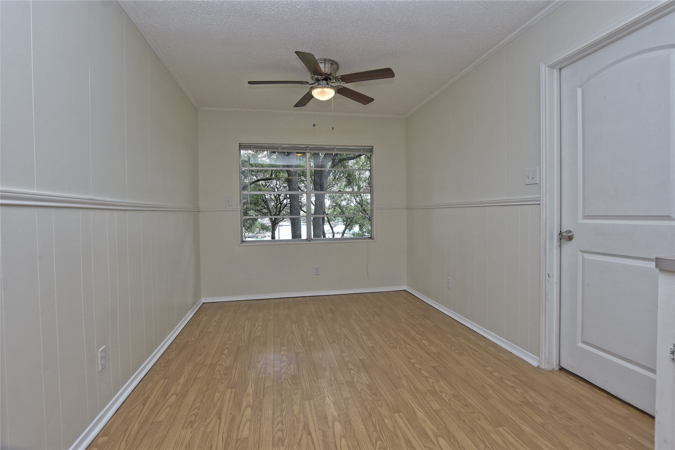 16013 Edwards Drive Austin, TX 78734 - Photo 10 of 30 Unfurnished room with wood finished floors, ceiling fan, a textured ceiling, wood walls, and crown molding