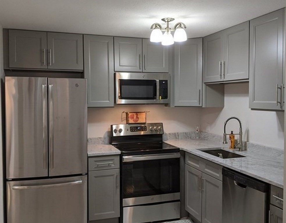 a kitchen with refrigerator a microwave a sink and cabinets