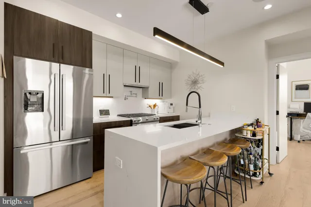 a kitchen with stainless steel appliances a refrigerator a stove a sink and white cabinets