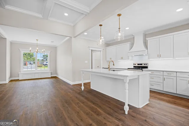 a kitchen with stainless steel appliances kitchen island wooden floors stove and white cabinets