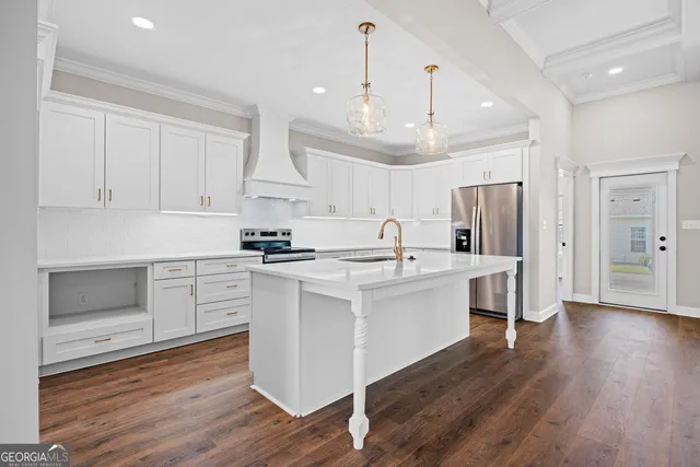 a kitchen with stainless steel appliances white cabinets a sink a stove a refrigerator and wooden floor