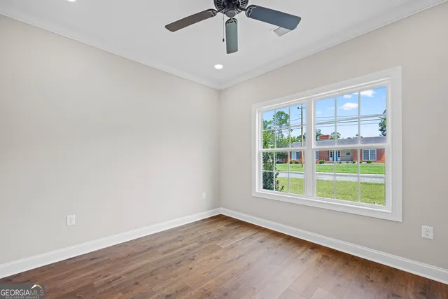 a view of an empty room with wooden floor and a window