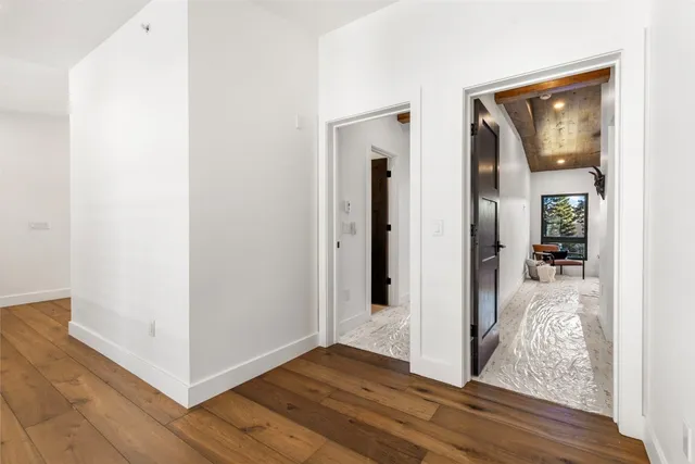 a view of a hallway with wooden floor and a living room