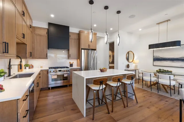 a kitchen with stainless steel appliances a table chairs sink and microwave