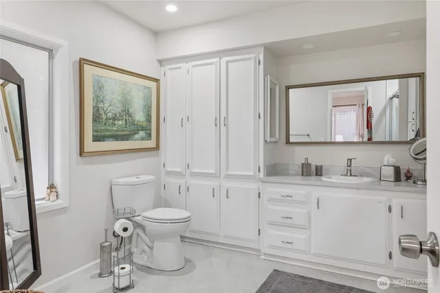 a bath room with a toilet a sink and a mirror