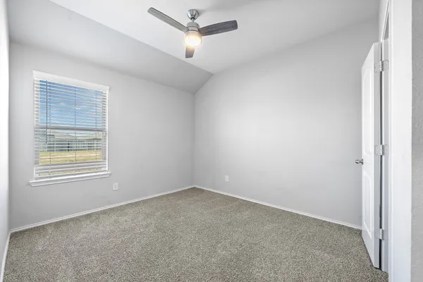 an empty room with a window and ceiling fan