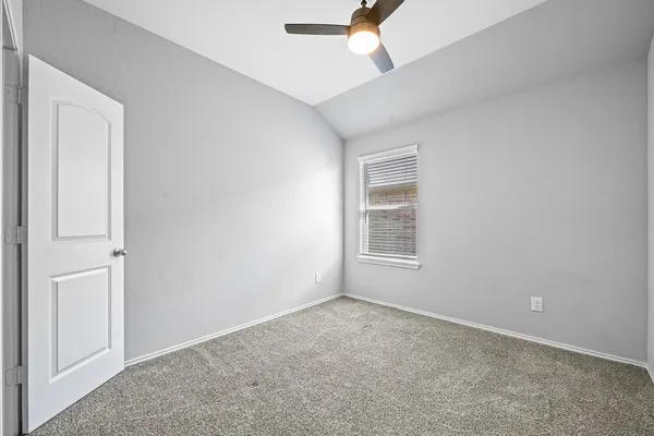 an empty room with windows and fan
