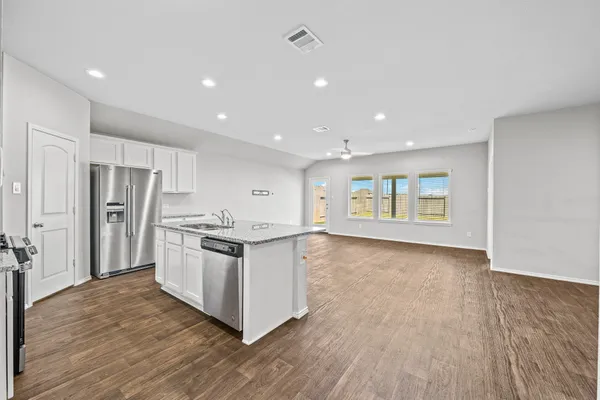 a kitchen with stainless steel appliances granite countertop a stove a refrigerator and a refrigerator with wooden floors
