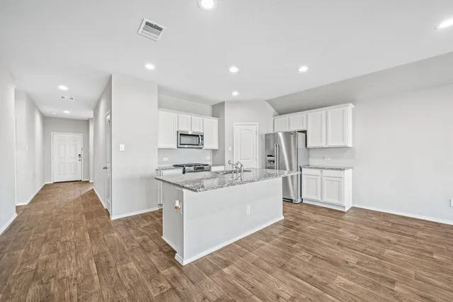 a kitchen with stainless steel appliances a stove top oven a sink and a refrigerator