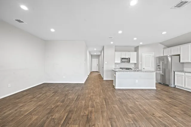 a view of an empty room with a window and wooden floor