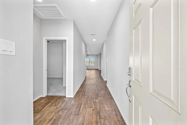 a view of a hallway with wooden floor and a bathroom