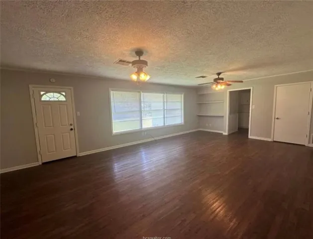 an empty room with wooden floor chandelier fan and windows