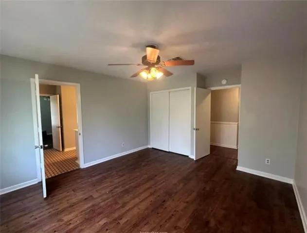 a view of an empty room with wooden floor and a chandelier fan