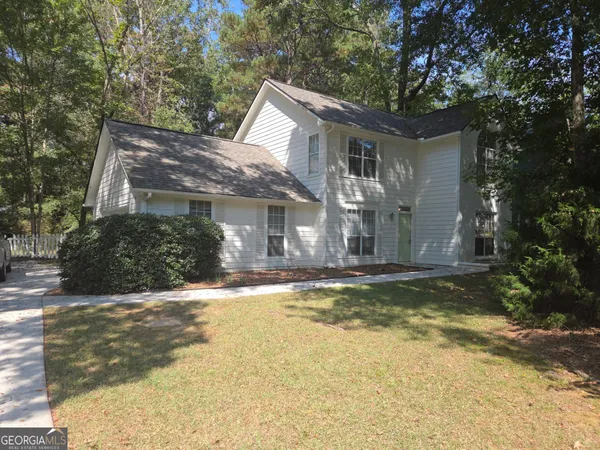 a view of a house with a yard and large tree