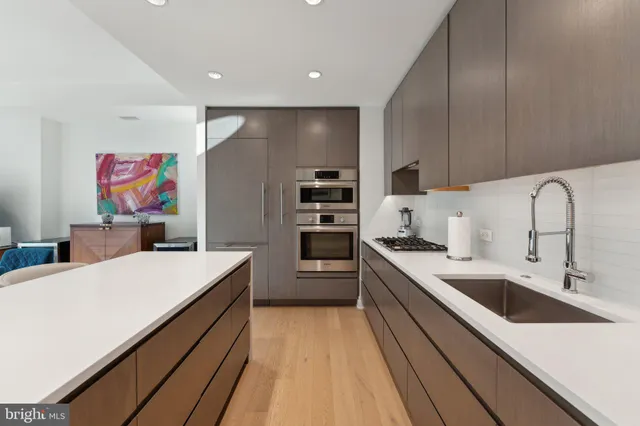 a large kitchen with stainless steel appliances a sink dishwasher a refrigerator and a stove with wooden floor