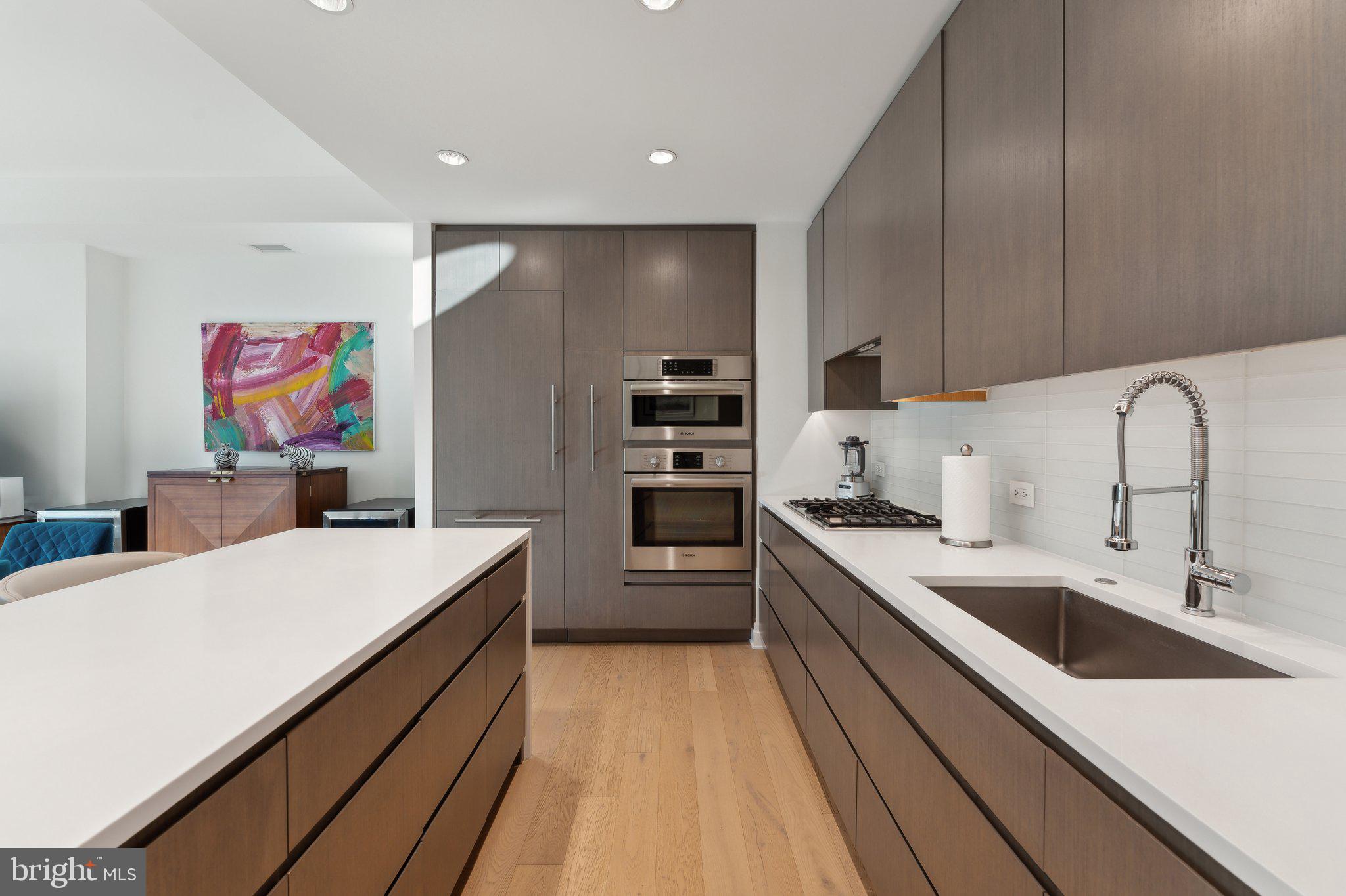 2501 M Street Northwest, Unit 207 Washington, DC 20037 - Photo 8 of 30 a large kitchen with stainless steel appliances a sink dishwasher a refrigerator and a stove with wooden floor